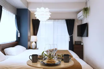 a room with two beds and a table with wine glasses at Latte Urban Elegance Kinshicho, 5min walk to Station in Tokyo