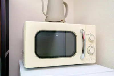 a microwave with a cup on top of it at Shibuya Urban Retreat - \u6771\u4eac\u89b3\u5149\u306b\u4fbf\u5229 - \u4ee3\u3005\u6728\u4e0a\u539f\u99c5\u304b\u3089\u5f92\u6b691\u5206 in Tokyo