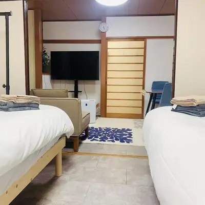 a living room with two beds and a television at Japan House \u6e6f\u5cf6 in Tokyo