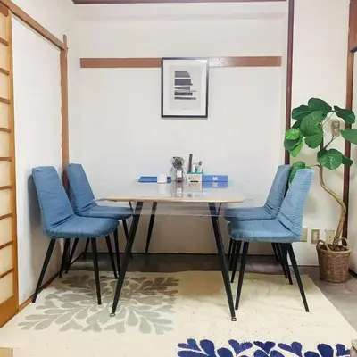 a dining room table with blue chairs and a plant at Japan House \u6e6f\u5cf6 in Tokyo