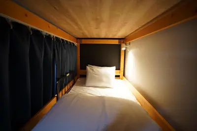 a small bed with a white pillow in a room at Hotel iemirai SHINJUKU 3min train ride to Shinjuku Station in Tokyo