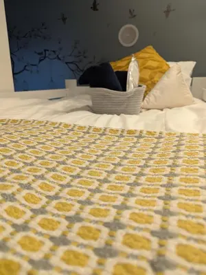 a bed with a yellow and white blanket on it at Cozy stay with direct access to Narita & Haneda in Tokyo