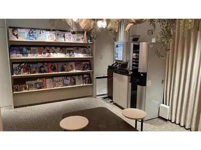 a room with a kitchen with a refrigerator and tables at GLANSIT AKIHABARA