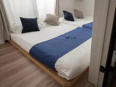 two beds with blue and white sheets in a room at \u685c\u306e\u5ddd64 \u6c60\u888b\u99c5C6\u53e3 8\u5206 2-11\u4eba\u4e28Ikebukuro JR Line C6 Exit 8 minutes 2-11 people in Tokyo