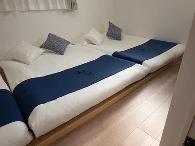two beds with blue and white sheets and pillows at \u685c\u306e\u5ddd64 \u6c60\u888b\u99c5C6\u53e3 8\u5206 2-11\u4eba\u4e28Ikebukuro JR Line C6 Exit 8 minutes 2-11 people in Tokyo