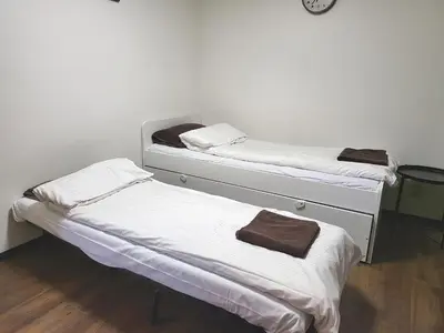 two beds in a room with a clock on the wall at Holiday Anytel Shinjuku#3 in Tokyo
