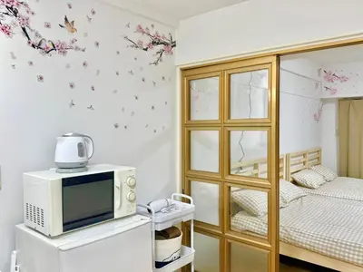 a room with a microwave and a bed with flowers on the wall at Shinjuku Waseda\u30cf\u30a6\u30b9 T4 in Tokyo