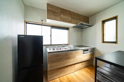 a kitchen with a sink and a black refrigerator at Kokoon Hotel Aoto in Tokyo
