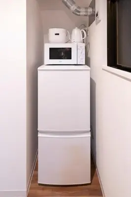 a microwave sitting on top of a white refrigerator at SATELLITE HOTEL Komagome \u30b5\u30c6\u30e9\u30a4\u30c8\u30db\u30c6\u30eb\u99d2\u8fbc in Tokyo