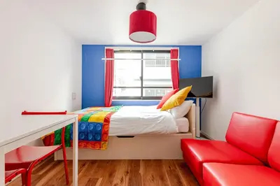 a small bedroom with a bed and a red chair at \u6d45\u8349\u6a4b201 in Tokyo