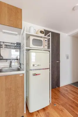 a kitchen with a microwave on top of a refrigerator at \u6d45\u8349\u6a4b202 in Tokyo