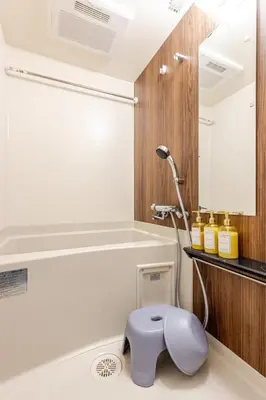 a bathroom with a blue stool in front of a bathtub at \u6d45\u8349\u6a4b202 in Tokyo