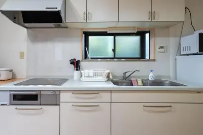 a kitchen with white cabinets and a sink and a window at Y's INN 北砂 101T in Tokyo