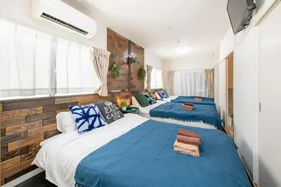 a bedroom with three beds with blue and white sheets at Bibarudy Shinagawa -\u54c1\u5ddd\u30a8\u30ea\u30a2\u99c5\u524d1\u52068\u540d \u7fbd\u7530\u7a7a\u6e2f25\u5206- in Tokyo