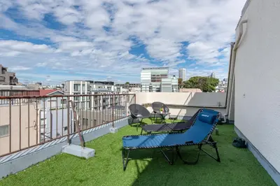a balcony with a blue chair and chairs on a roof at \u8429\u5c3e\u30d3\u30eb\u56db\u968e\u4e94\u968e in Tokyo