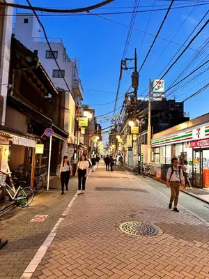 a group of people walking down a street at night at \u5317\u5343\u4f4f\u306e\u4e00\u8ed2\u5bb6\uff4b3 in Tokyo