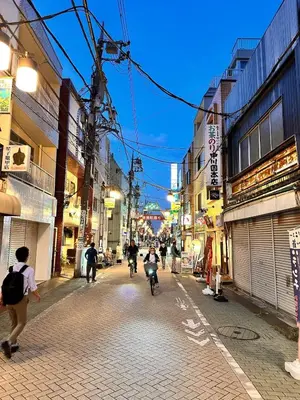 a group of people riding bikes down a city street at \u5317\u5343\u4f4f\u306e\u4e00\u8ed2\u5bb6\uff4b3 in Tokyo