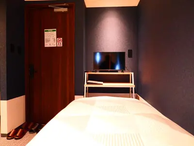 a bedroom with a bed and a tv on a wall at ForYou Honancho \u65b9\u5357\u753a in Tokyo