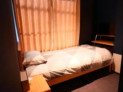 a bed in a room with a window and a bedskirtspectspectspectspects at ForYou Honancho \u65b9\u5357\u753a in Tokyo