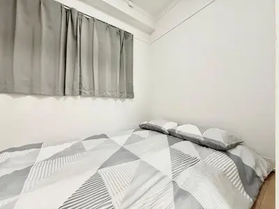a bedroom with a bed with a gray and white comforter at Shinjuku Waseda home4 in Tokyo