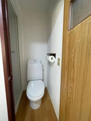 a bathroom with a toilet and a wooden door at \u548c\u98a8\u5c0f\u7b51\u3068\u4eac\u753a\u5c4b in Tokyo