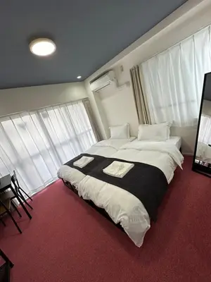 a bedroom with a large bed in a room with windows at \u798f\u30db\u30c6\u30eb402 in Tokyo