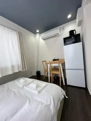 a room with a bed and a refrigerator and a table at \u798f\u30db\u30c6\u30eb402 in Tokyo