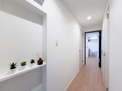 a hallway with white walls and white shelves with plants at Asakusa 801 Triple Room in Tokyo
