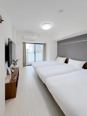 a hotel room with two beds and a television at Asakusa 802 Triple Room in Tokyo