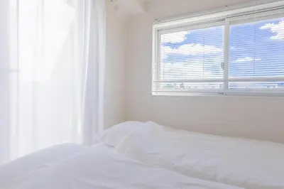 a white bedroom with a bed and a window at Emilio Nishi Shinjuku in Tokyo