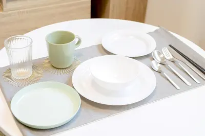 a table with white plates and a cup and forks and spoons at Emilio Nishi Shinjuku in Tokyo