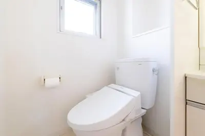 a white bathroom with a toilet and a window at Emilio Nishi Shinjuku in Tokyo