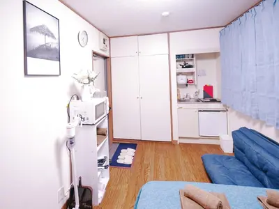 a living room with a blue couch and a kitchen at \u62bc\u4e0a\u8f66\u7ad9\u6b65\u884c5\u5206\u949f\u7684\u65b0\u623f\u6e90 \u514d\u8d39wifi \u7535\u8f66\u76f4\u8fbe\u6210\u7530\u673a\u573a\u548c\u7fbd\u7530\u673a\u573a in Tokyo