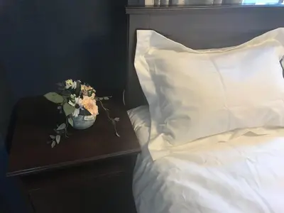 a bed with a pillow and flowers on a table at \u4e09\u30ce\u8f2a301 in Tokyo