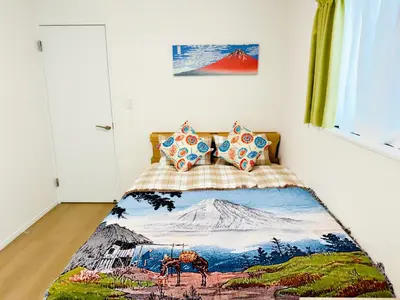 a bedroom with a bed with a painting of a mountain at Hao Bros Home Gemini A in Tokyo