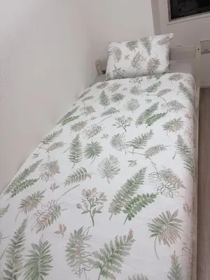 a bed with a white blanket with green leaves on it at Tulip Asakusa in Tokyo