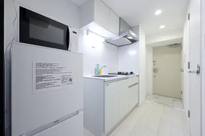 a kitchen with white cabinets and a tv on a wall at AlTERNA\u6075\u6bd4\u5bff in Tokyo
