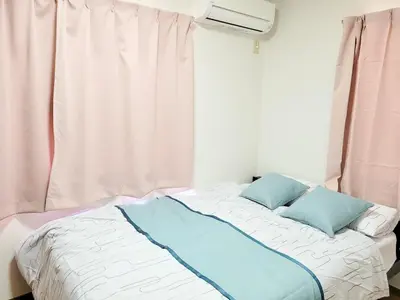 a bed with two blue pillows sitting next to a window at \u6771\u9577\u5d0e\u6238\u5efa\u3066 \u6771\u9577\u5d0e\u99c5\u304b\u3089\u5f92\u6b692\u5206 in Tokyo