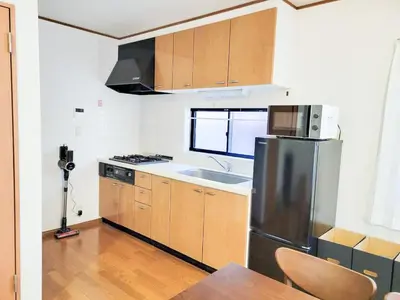 a kitchen with a stainless steel refrigerator and wooden cabinets at \u6771\u9577\u5d0e\u6238\u5efa\u3066 \u6771\u9577\u5d0e\u99c5\u304b\u3089\u5f92\u6b692\u5206 in Tokyo