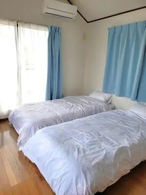 two beds in a bedroom with blue curtains at \u6771\u9577\u5d0e\u6238\u5efa\u3066 \u6771\u9577\u5d0e\u99c5\u304b\u3089\u5f92\u6b692\u5206 in Tokyo