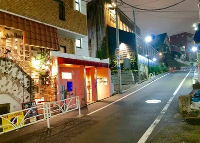 an empty city street at night with a building at A Cosy Daikanyama Stay at the Anime Sanctuary in Tokyo