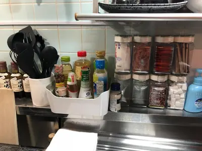 a kitchen counter with a shelf with spices and utensils at A Cosy Daikanyama Stay at the Anime Sanctuary in Tokyo