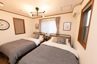 two beds in a room with a clock on the wall at \u30a8\u30d0\u30fc\u30db\u30ef\u30a4\u30c8\u6771\u5411\u5cf6 in Tokyo