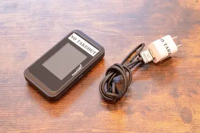 a cell phone hooked up to a usb adapter at \u30a8\u30d0\u30fc\u30db\u30ef\u30a4\u30c8\u6771\u5411\u5cf6 in Tokyo