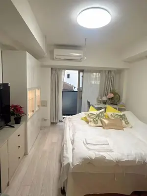 a white bedroom with a large bed and a television at ReimiMondo 303 in Tokyo