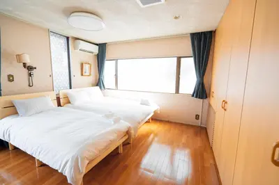 two beds in a room with a large window at \u5343\u5e74\u90b8 in Tokyo