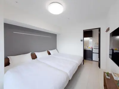 a bedroom with a large white bed and a kitchen at Asakusa 602 Triple Room in Tokyo