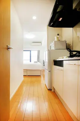 a kitchen with white cabinets and a wooden floor at Shinjuku-IEE in Tokyo