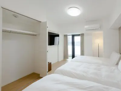 a white bedroom with two beds and a window at Asakusa 201 Quad room in Tokyo