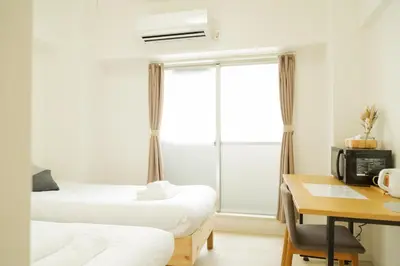 a bedroom with two beds and a desk and a window at Ikebukuro Twin Room in Tokyo